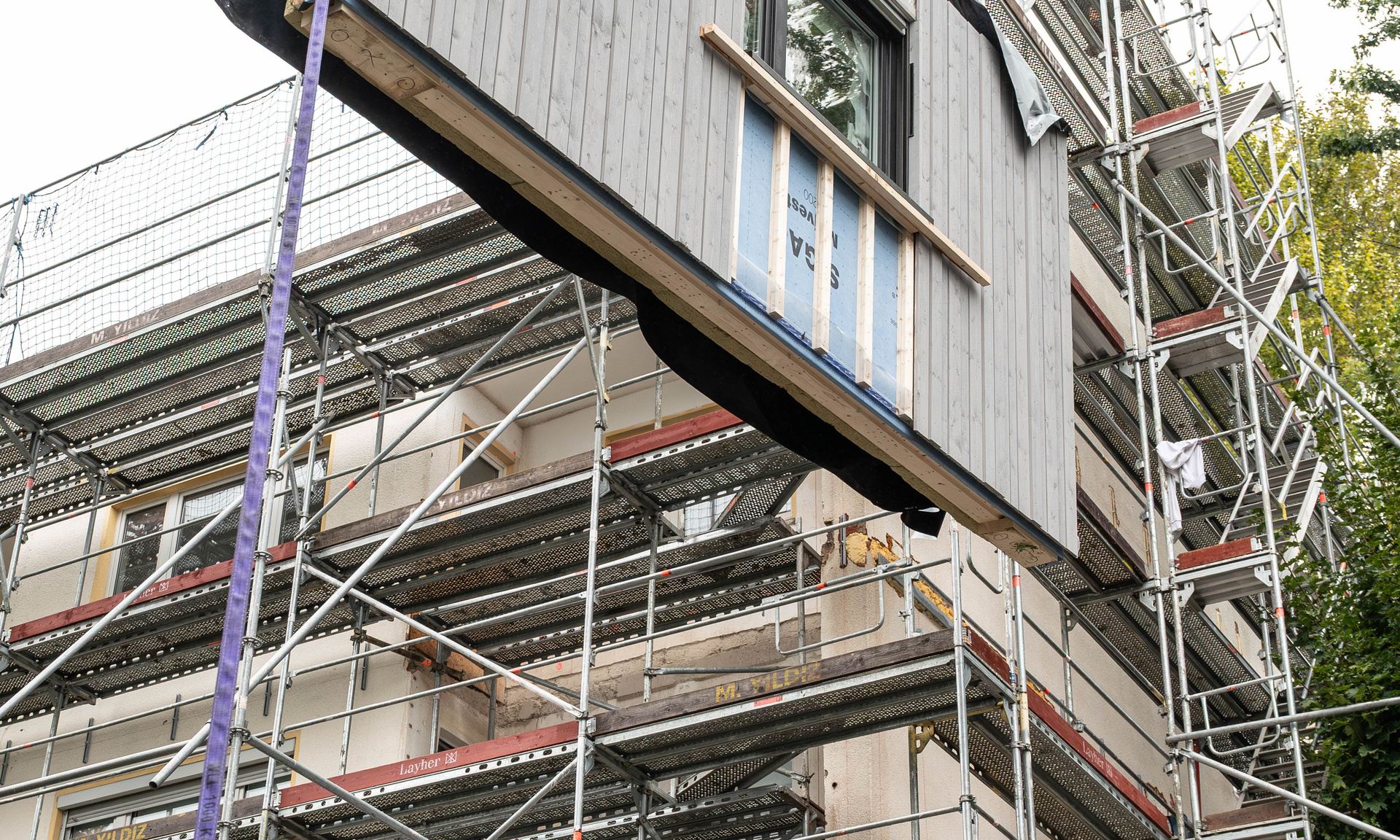 Ein Modul wird an die Fassade gehoben und eingepasst. 